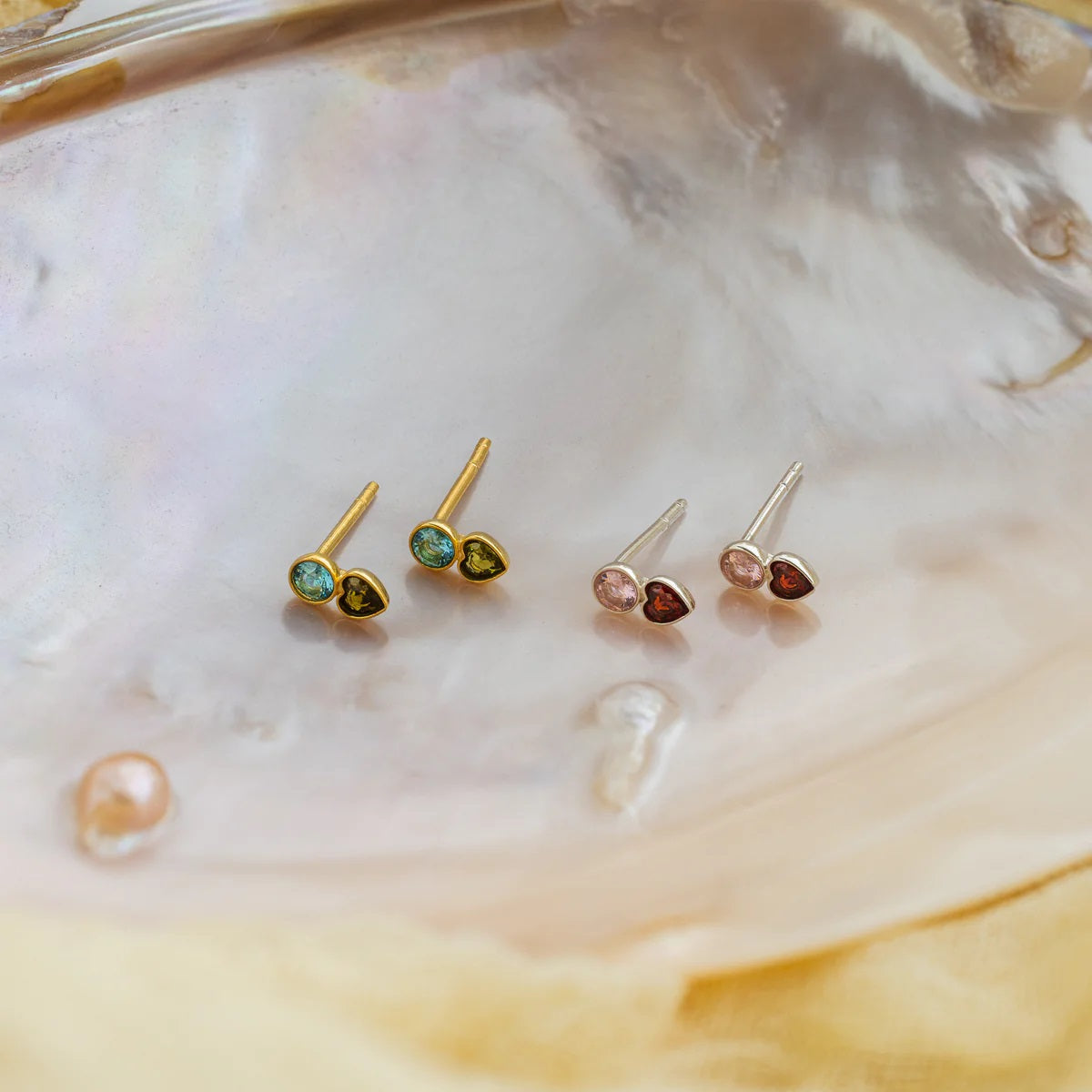 Set of heart-shaped gemstone earrings on a shell background